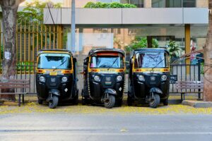 Authentic Indian auto rickshaw parked on a bustling street in India, surrounded by colorful storefronts and pedestrians