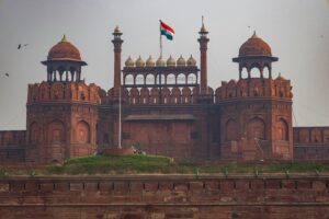 An ancient red sandstone fort with large imposing walls and intricate architecture, basking under the sun