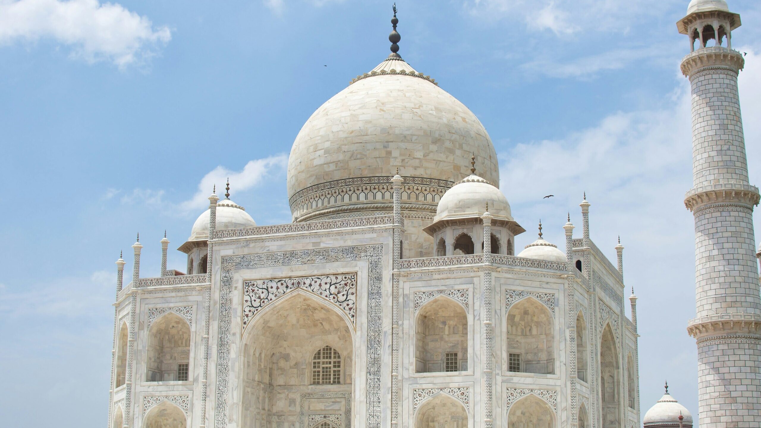view of the Taj Mahal under a clear blue sky, showcasing its iconic white marble architecture in Agra, India,