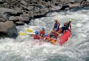 Group of people rafting through white-water rapids on the Ganges River in Rishikesh, one of Top 7 Adventure Activities 