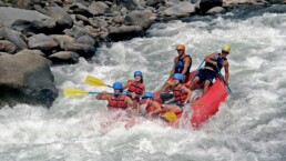 Group of people rafting through white-water rapids on the Ganges River in Rishikesh